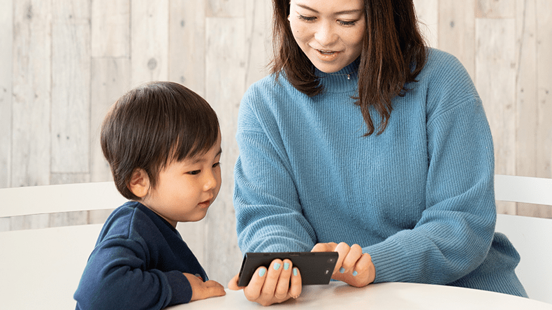 自動編集された進級テストの動画を一緒に確認する親子の画像